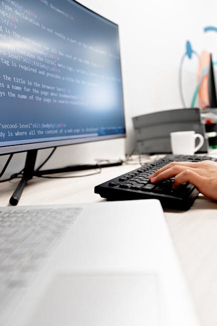 A close-up view of a computer screen displaying lines of colorful programming code with syntax highlighting, including various text colors such as blue, green, yellow, and red, on a dark background. T